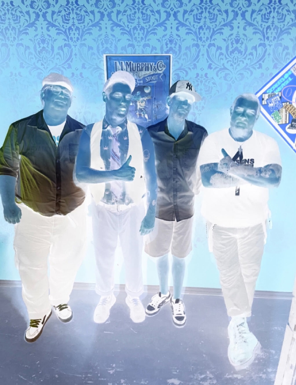 The four members of SHSC posing in a bar in front of a J.I. Murphy & Co. stout poster, colors inverted